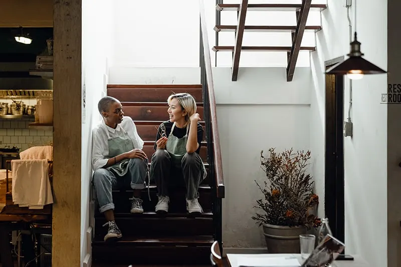 zwei weibliche Mitarbeiter plaudern während einer Pause auf Treppen