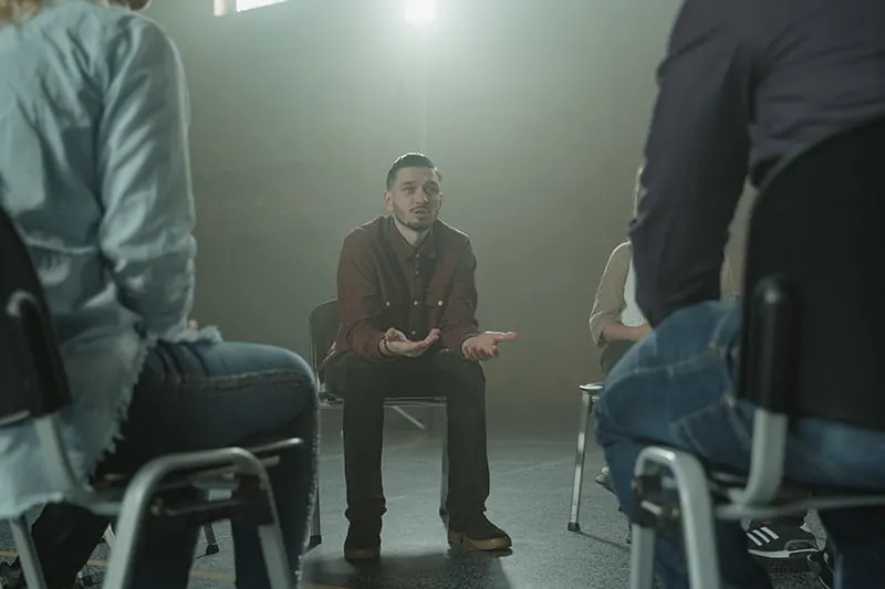 Ein Mann spricht mit der Familie, während er auf dem Stuhl bei der Therapie sitzt