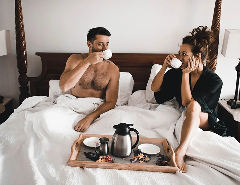 Ein Mann und eine Frau trinken zusammen Kaffee, während sie im Bett sitzen