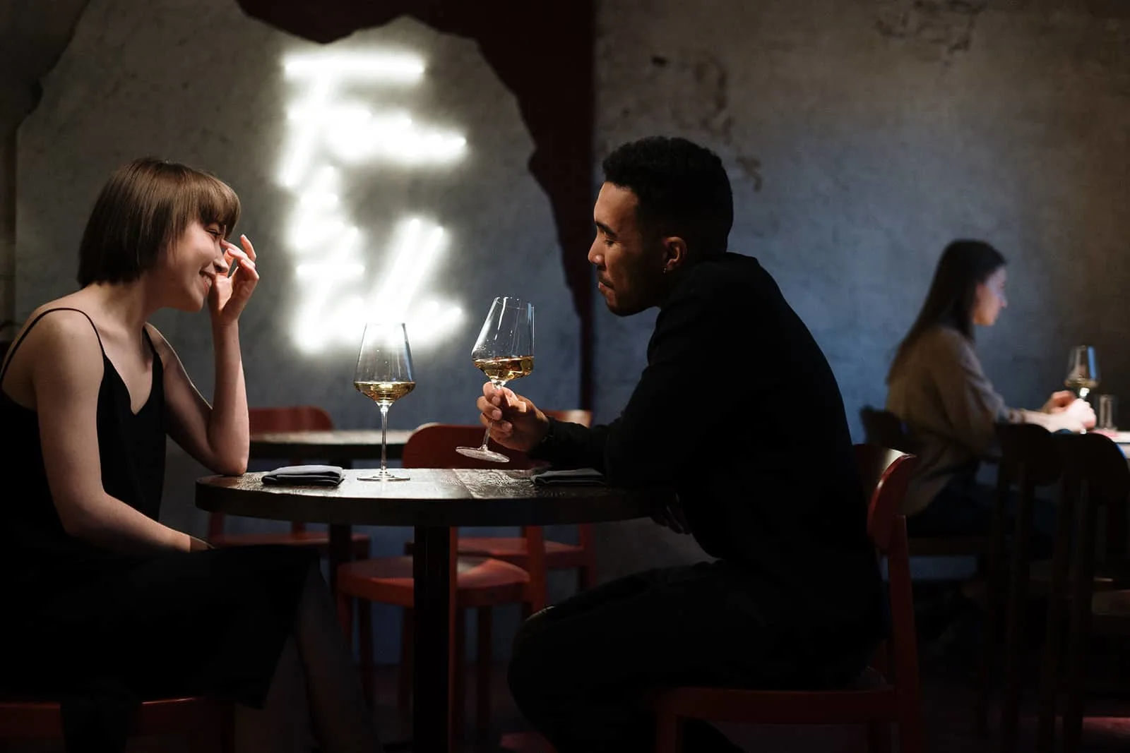 Ein Mann verführt eine Frau, während er im Restaurant ein Glas Wein hält