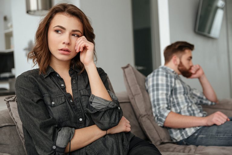 eine traurige Frau, die neben ihrem Freund auf der Couch sitzt