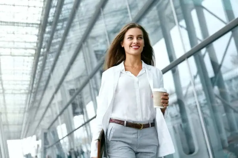 Eine junge Geschäftsfrau geht mit einem Glas in der Hand an der Firma vorbei
