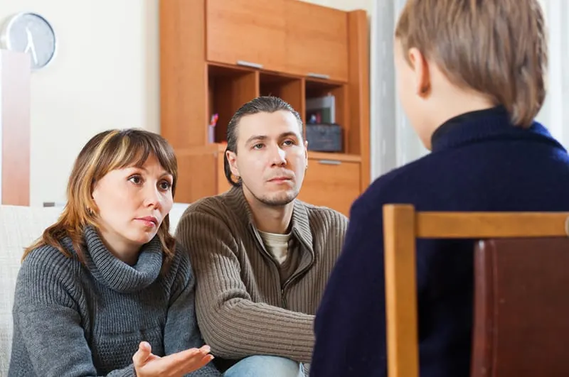 Eltern sprechen mit ihrem Kind, während sie vor ihm sitzen