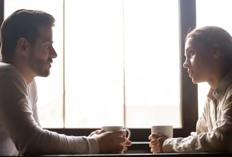 Ernsthafter Mann und Frau sprechen, während sie Kaffee zusammen trinken