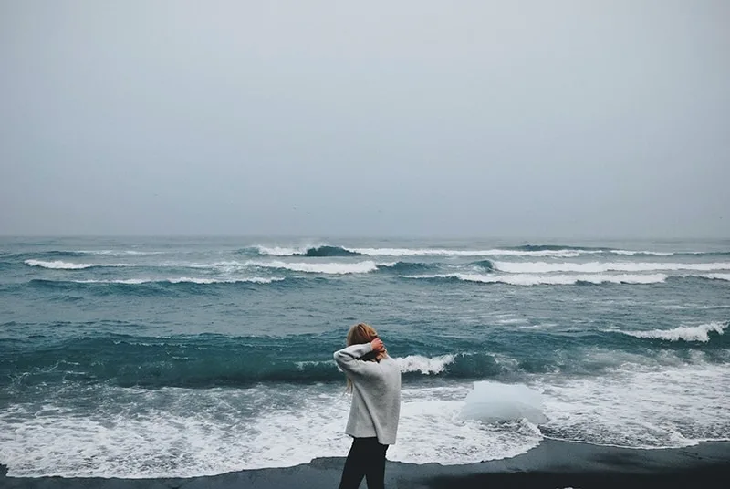 Frau, die während eines Seesturms neben der Küste geht