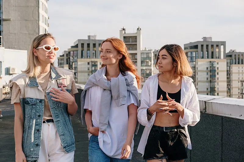 Frau mit Sonnenbrille im Gespräch mit ihren beiden Freundinnen beim gemeinsamen Gehen