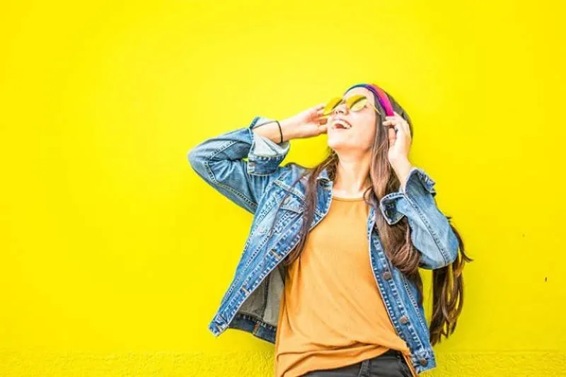 ein Mädchen vor einem gelben Hintergrund lacht