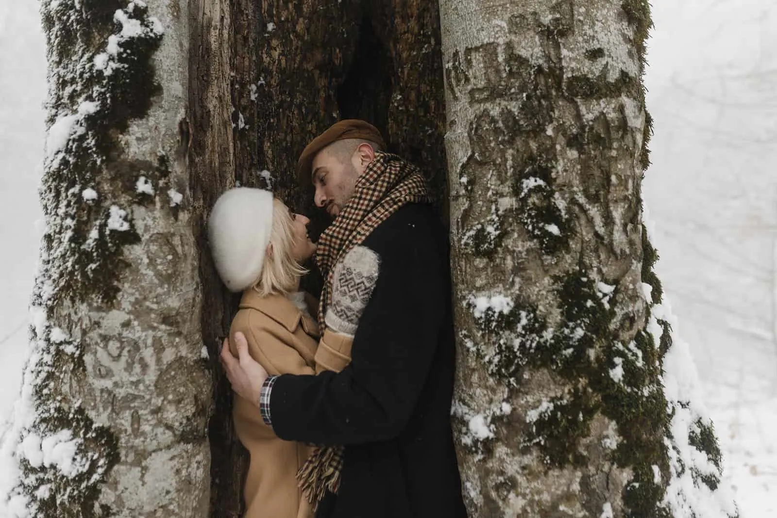 Liebespaar, das an einem verschneiten Tag in der Nähe des Baumes umarmt