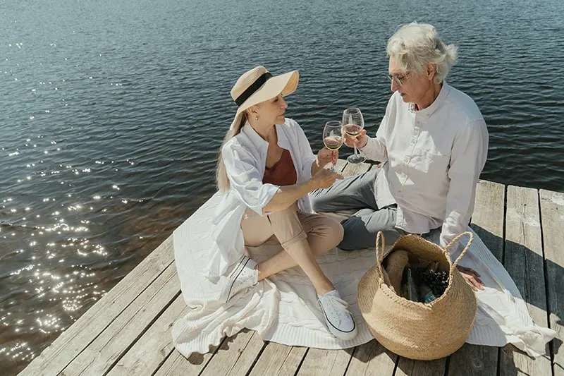 älteres Paar, das Wein auf dem Dock nahe dem Meer trinkt