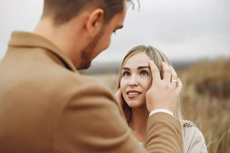 Ein Mann berührt die Haare einer Frau, während er einer Frau gegenübersteht