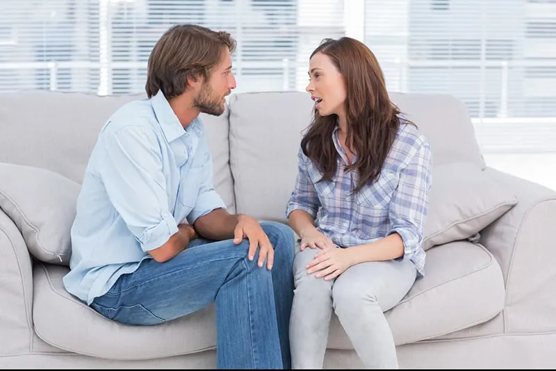 Ein Mann und eine Frau streiten sich, während sie auf der Couch sitzen