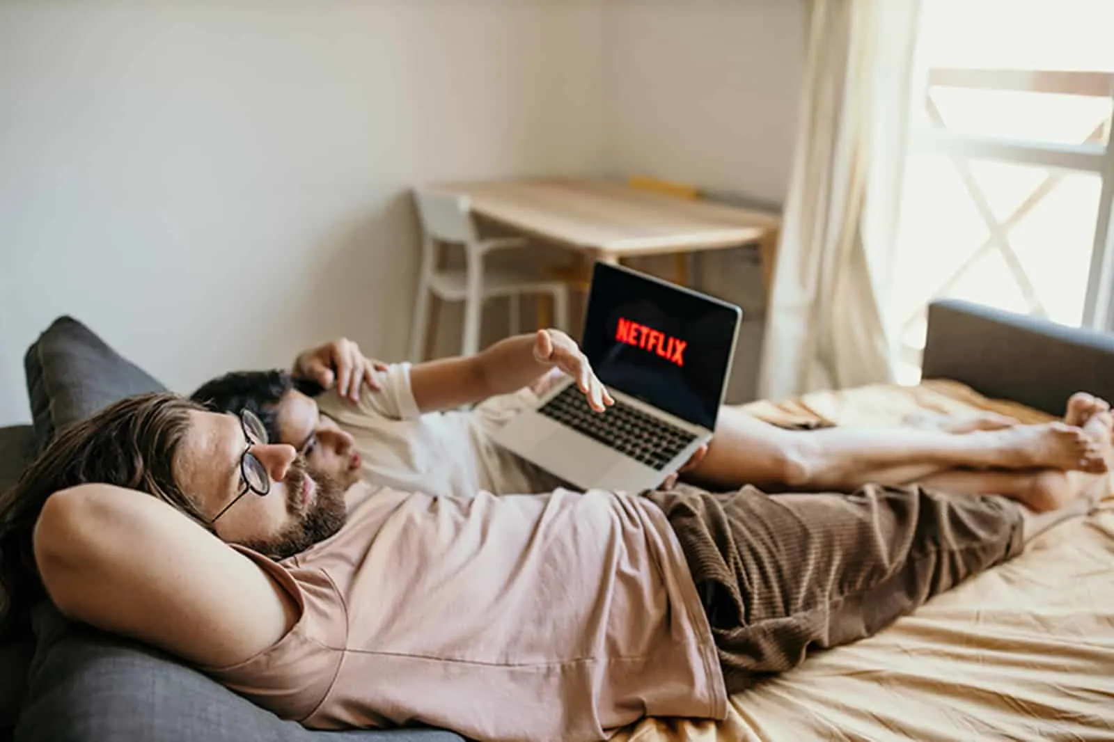 ein Paar, das in einem Bett liegt und Netflix auf einem Laptop beobachtet