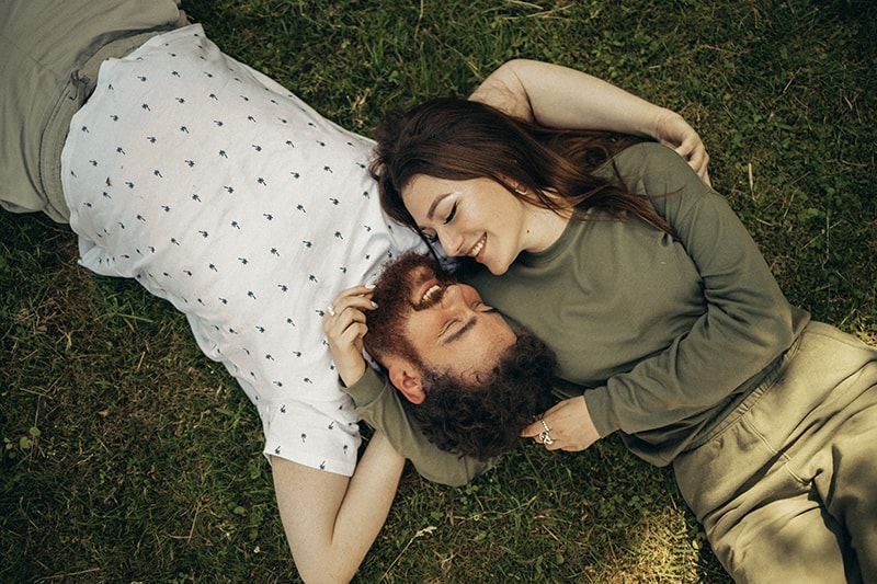 ein liebevolles Paar, das sich gegenübersteht, während es im Gras liegt und kuschelt
