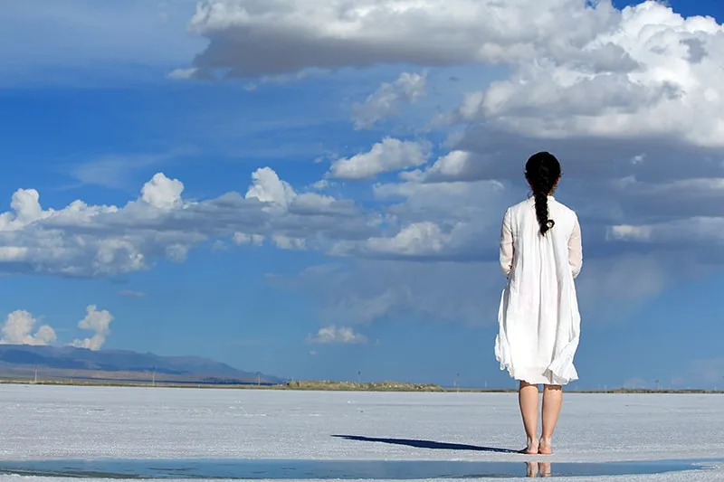 eine Frau, die am Strand steht und die Wolken betrachtet