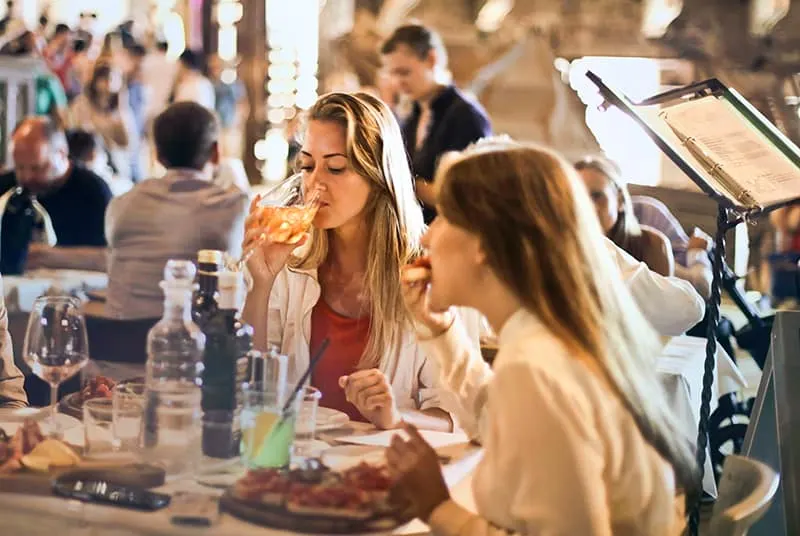 eine Frau, die Wein trinkt, während sie mit einer Freundin im Restaurant sitzt