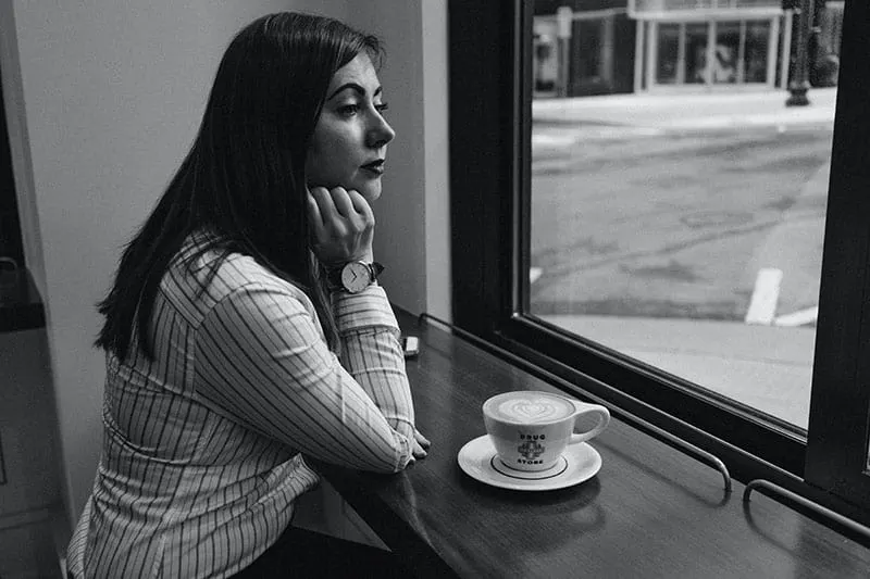 eine Frau, die alleine im Café am Fenster sitzt