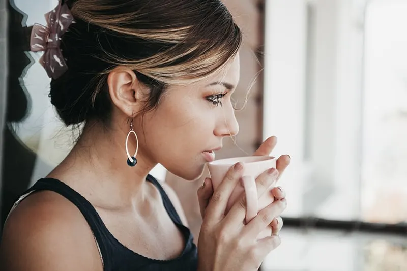 eine Frau, die gerade Kaffee trinken will und nachdenklich aussieht