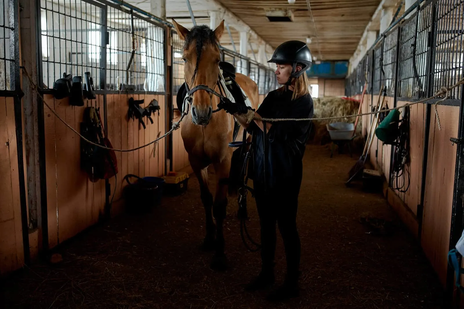 eine Frau, die mit einem Pferd in einem Stall steht