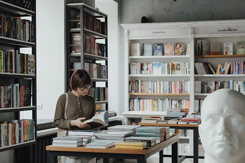 eine Frau, die ein Buch hält, während sie in einem Buchladen steht