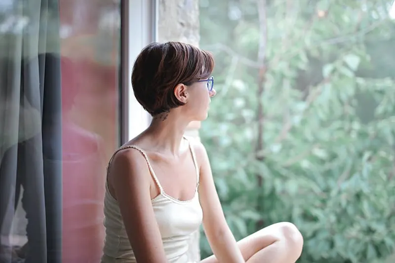 eine Frau, die auf der Fensterbank sitzt und nachdenkt
