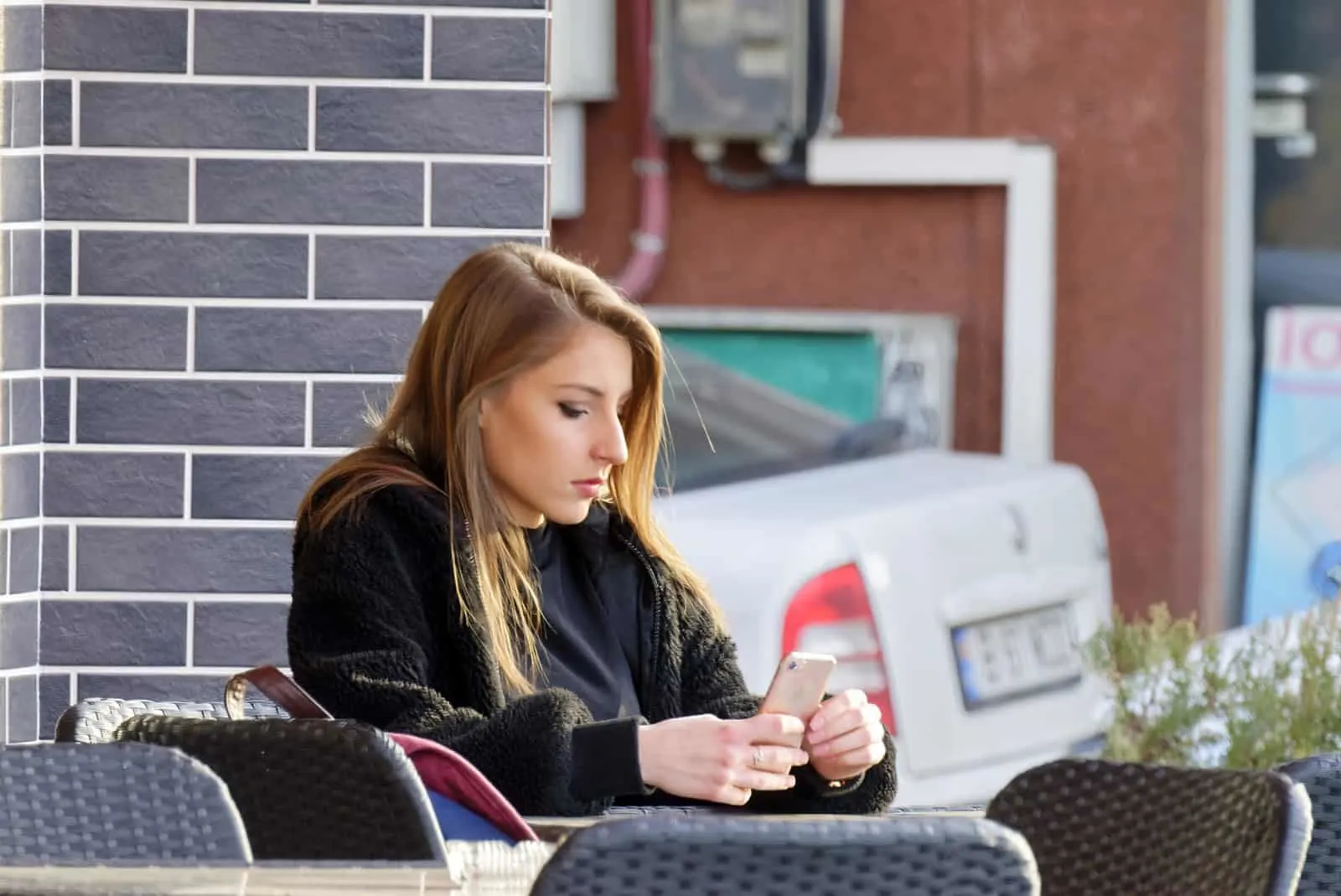 ernsthafte Frau, die ein Smartphone beim Sitzen im Café betrachtet