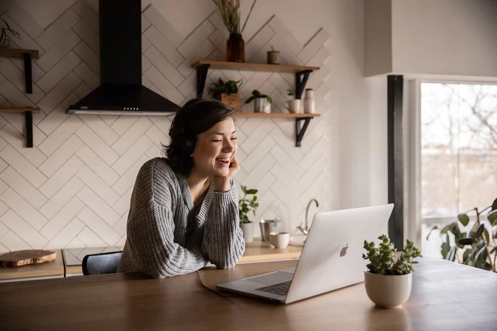 lächelnde Frau, die über Laptop in der Küche spricht