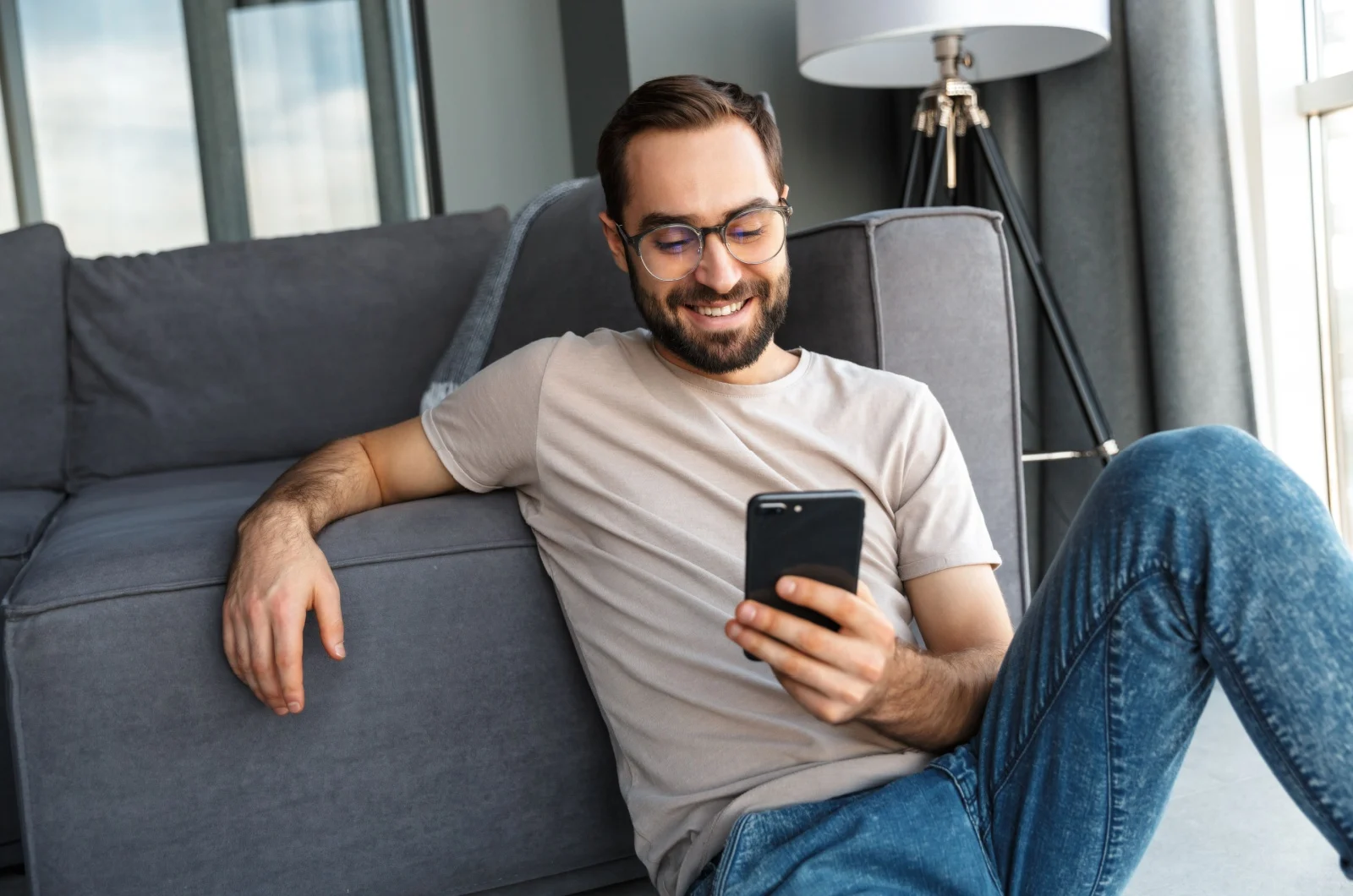 laechelnder Mann tippt am Telefon