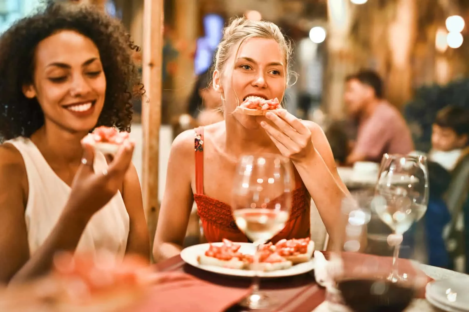zwei Freundinnen, die in einem Restaurant essen, während sie abhängen
