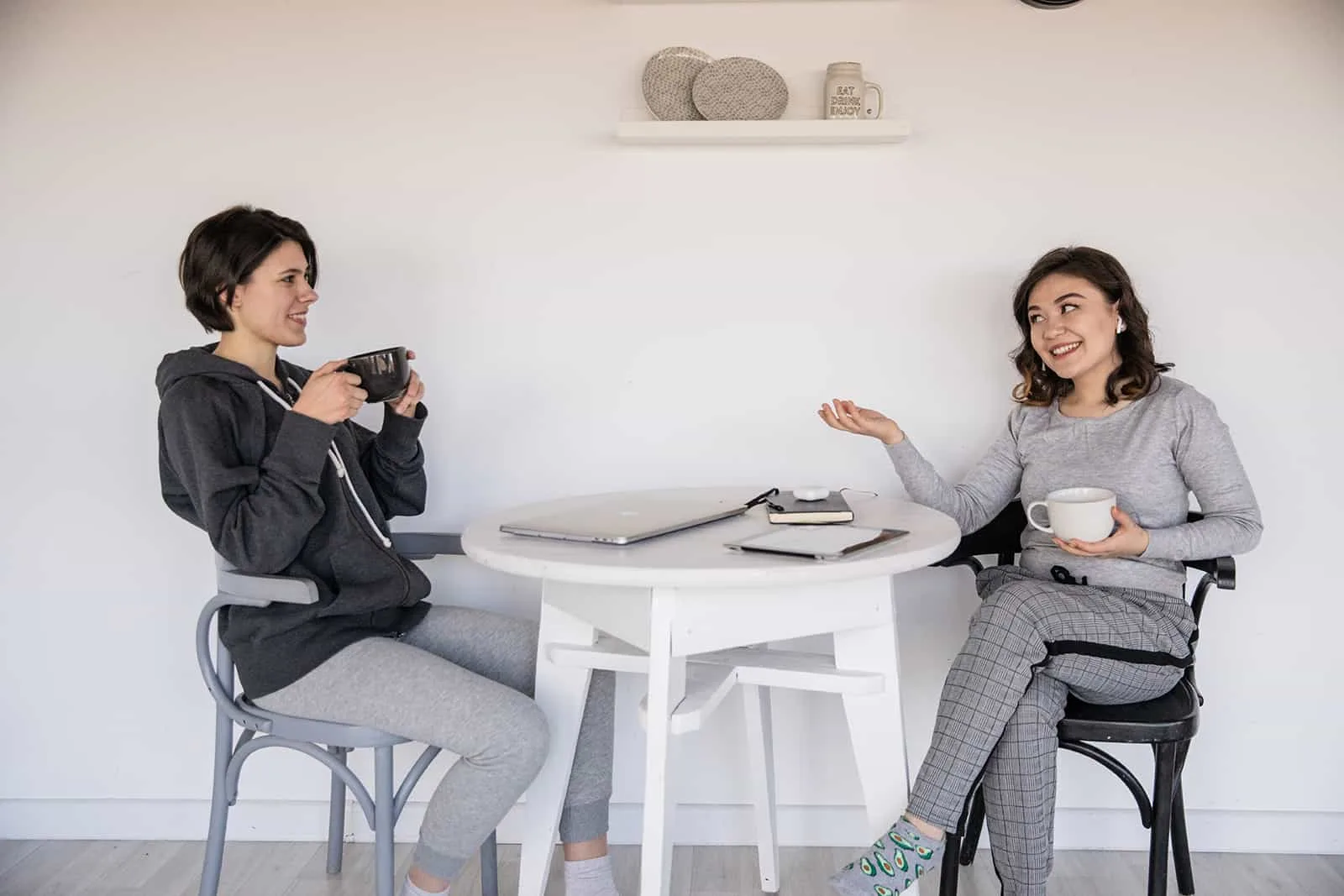zwei positive Freundinnen, die sich unterhalten und gemeinsam Kaffee trinken
