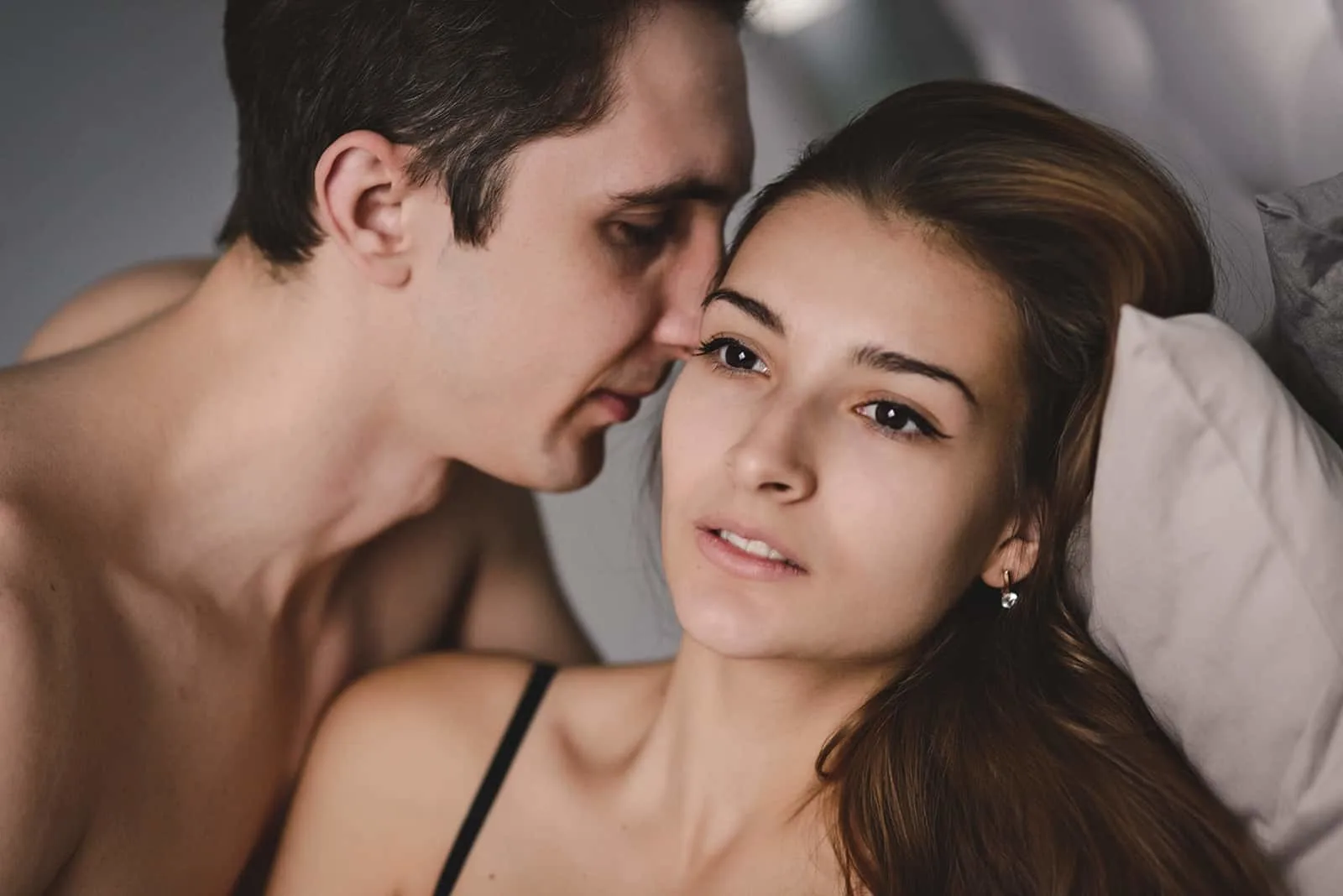 Ein Mann kuschelt mit seiner nachdenklichen Freundin im Bett