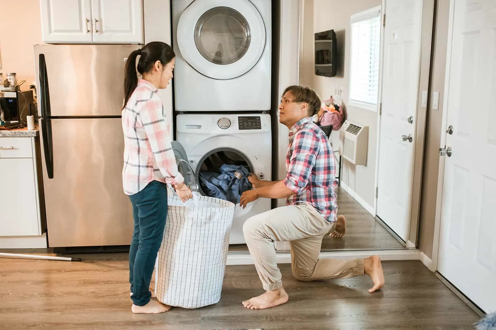 Ein Mann hilft ihrer Frau, Wäsche aus einer Waschmaschine zu holen in einen Korb