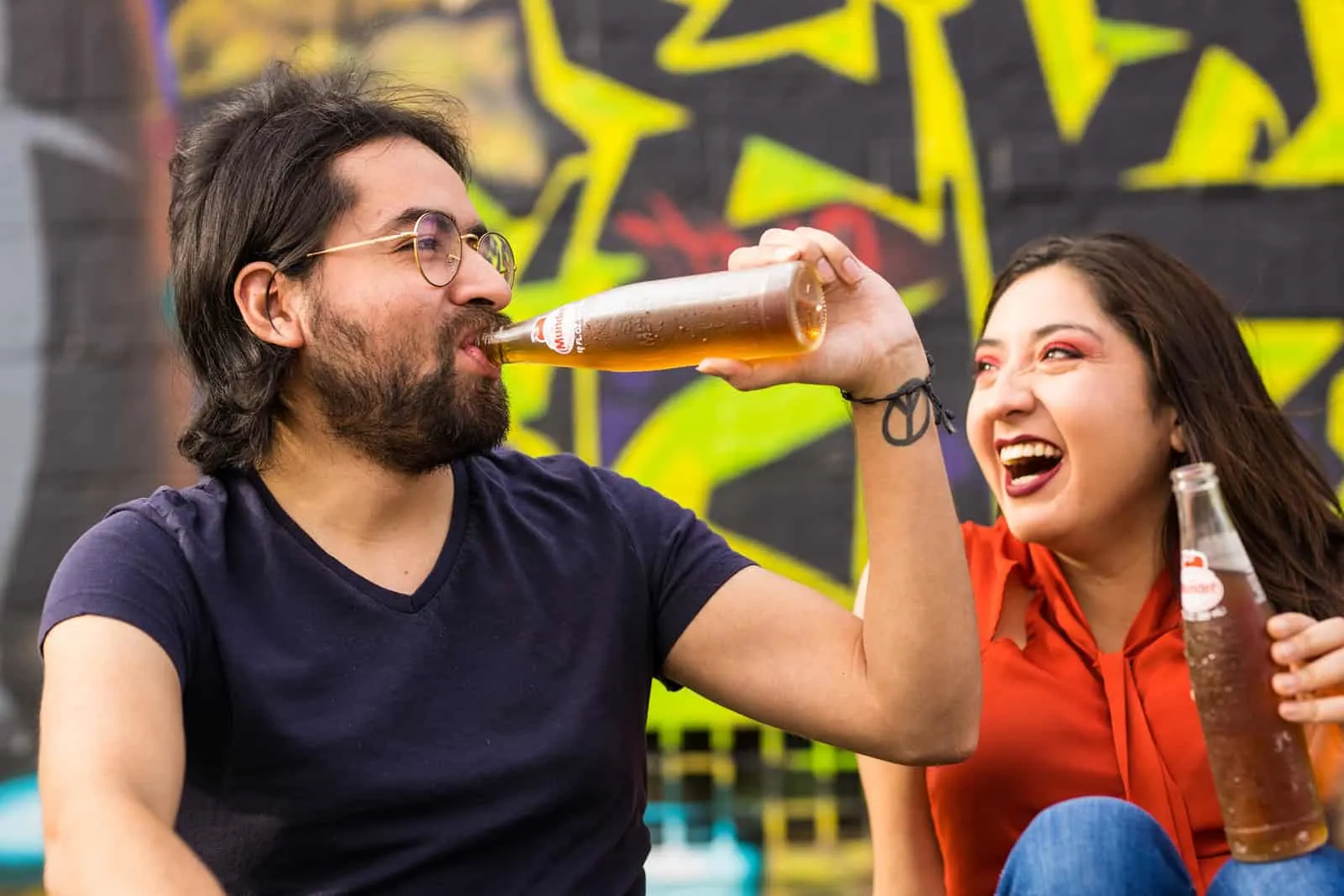 Ein Mann trinkt aus der Flasche in der Nähe der lächelnden Frau, die ihre Flasche mit einem Getränk hält