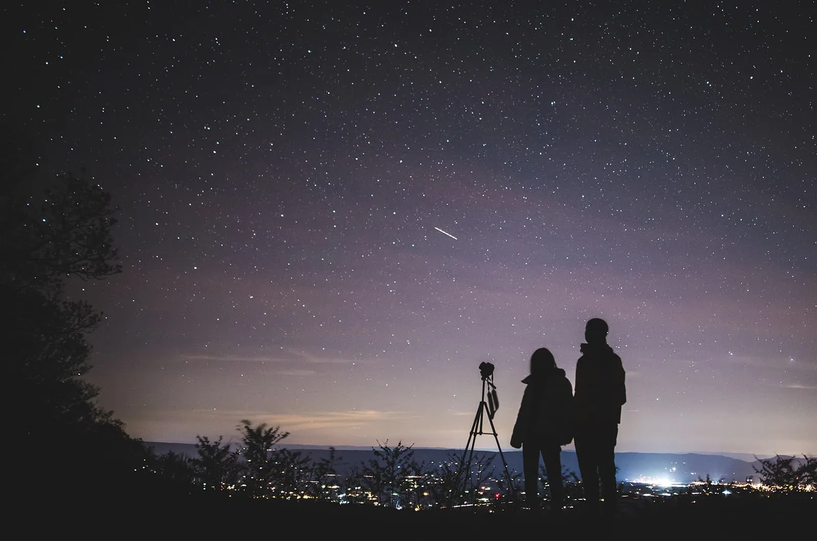 Ein Mann und eine Frau beobachten Sterne außerhalb der Stadt