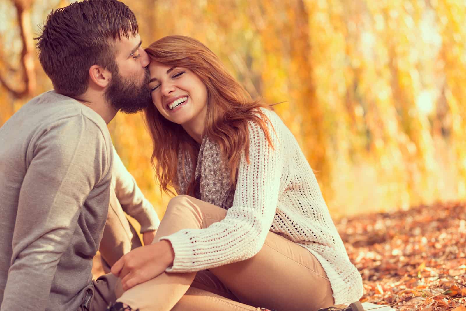 Ein Mann und eine Frau genießen und sitzen im Herbst auf trockenen Blättern