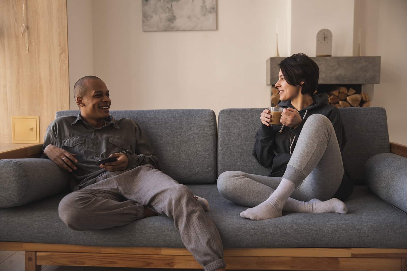 ein Paar sitzt auf der Couch und redet und trinkt zusammen Kaffee