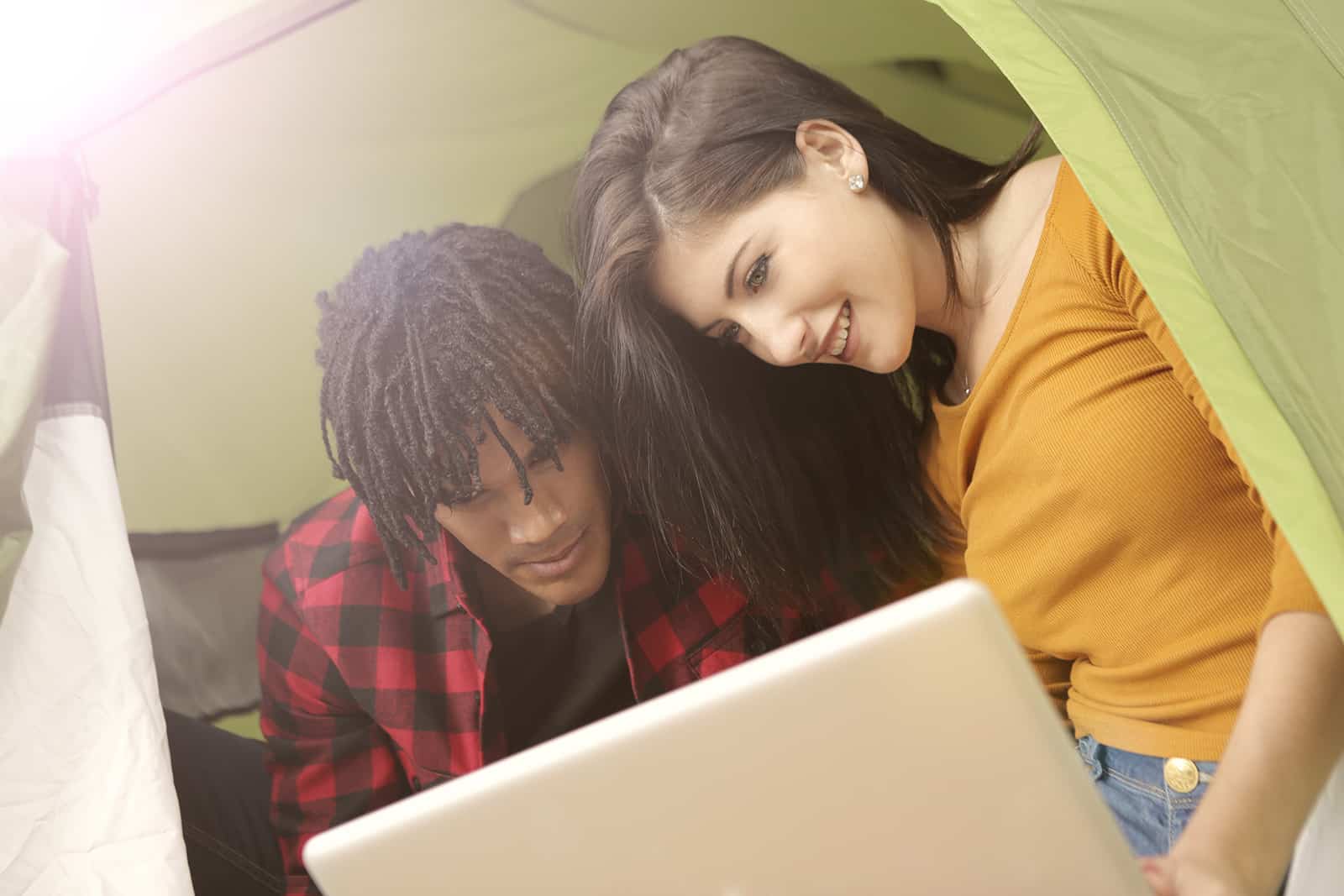 Ein Paar, das mit einem Laptop im Campingzelt sitzt
