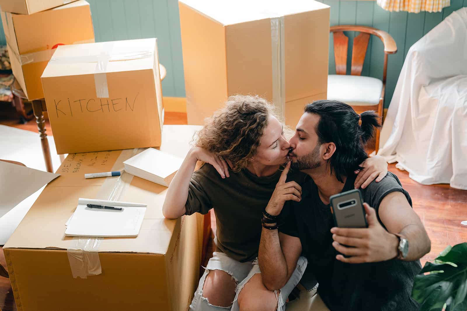 Ein küssendes Paar, das ein Selfie in einem neuen Zuhause macht