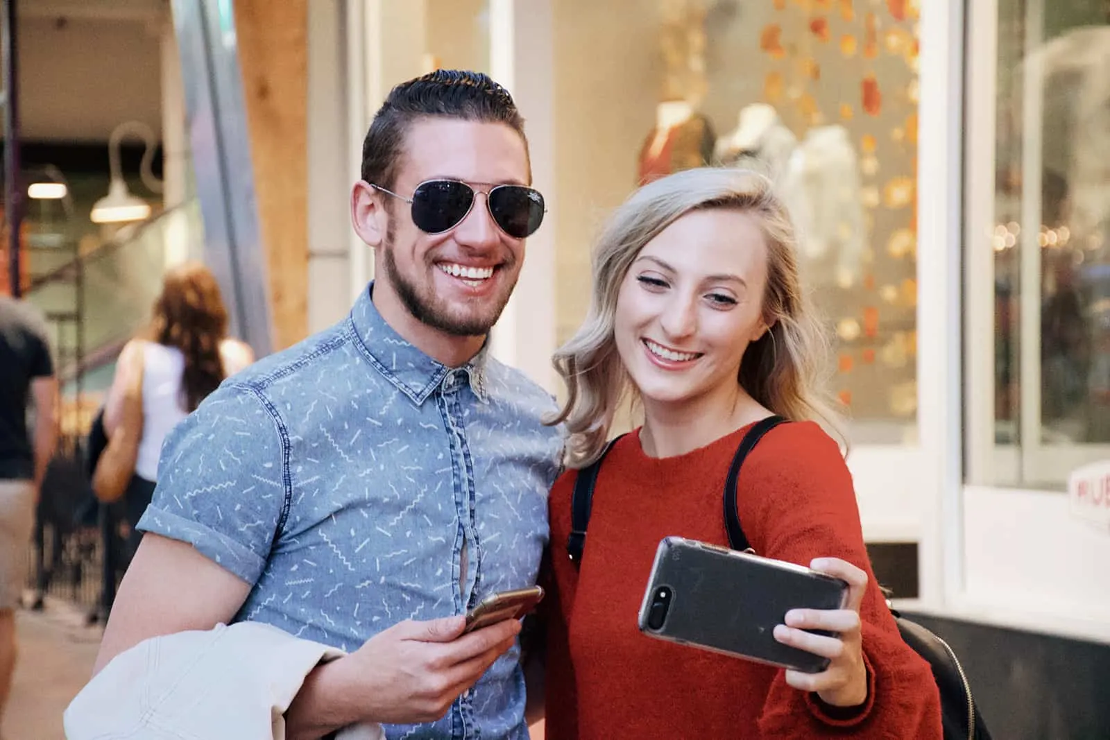 Ein lächelnder Mann und eine Frau machen ein Selfie, während sie im Einkaufszentrum stehen