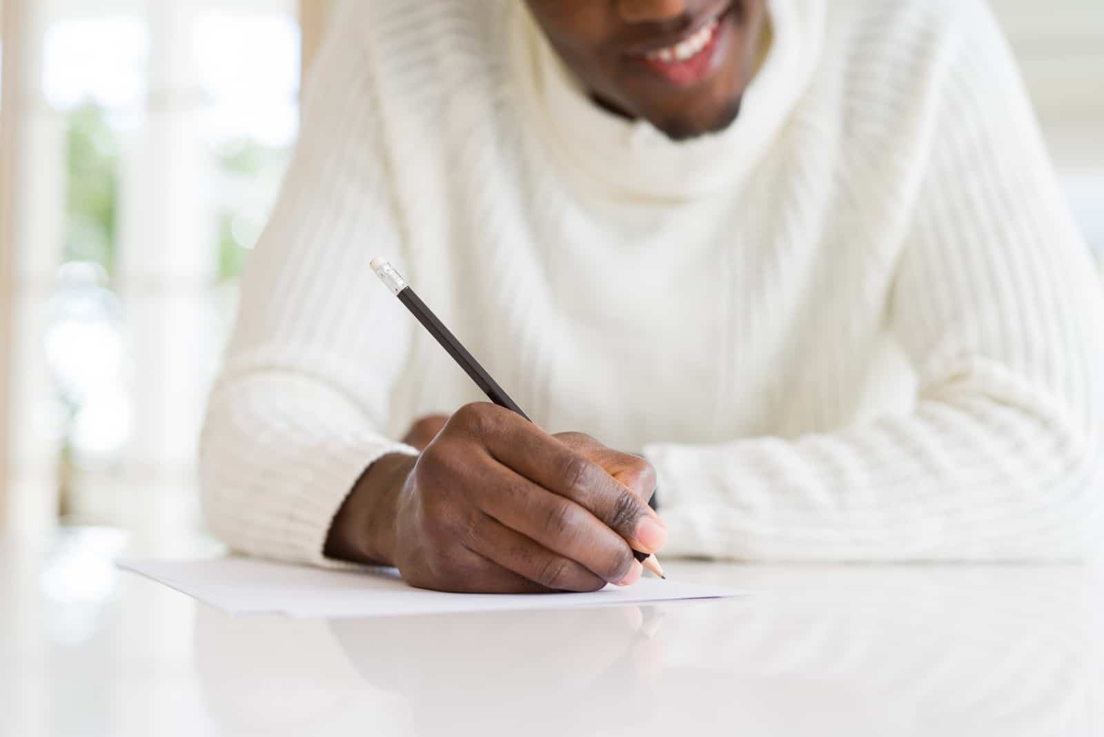 Ein lächelnder schwarzer Mann schreibt einen Brief