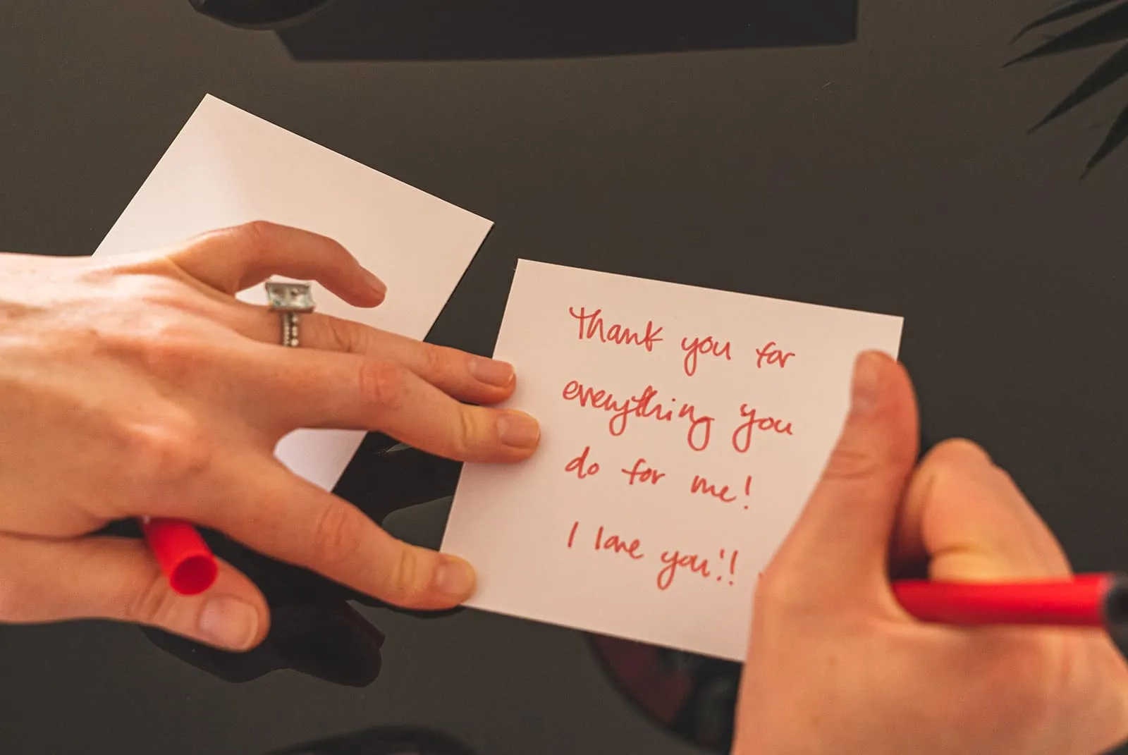Frau, die eine Nachricht auf eine Notiz mit einem roten Stift schreibt