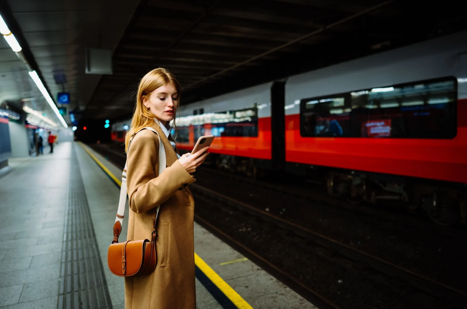 Frau haelt ein Telefon in der U-Bahn