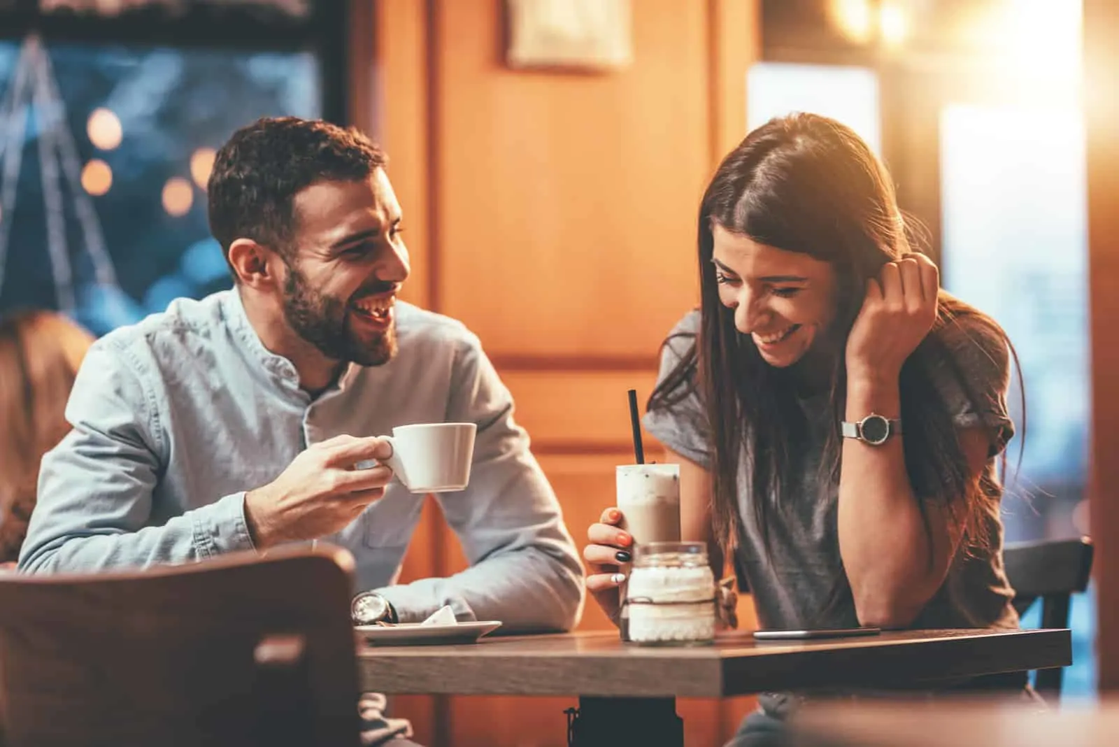 In einem Café trinkt ein lächelndes Paar Kaffee und redet