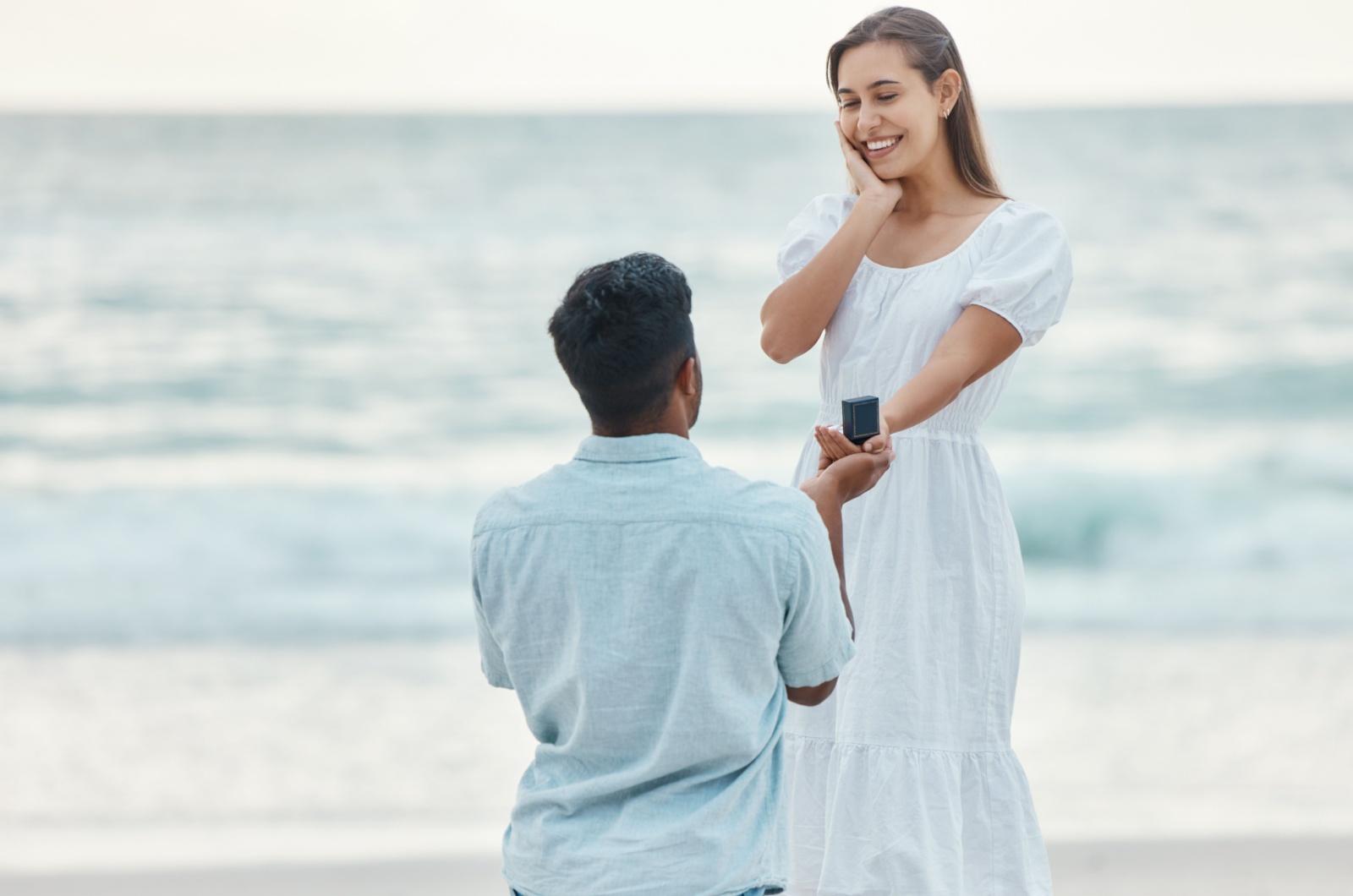 Mann macht Frau am Strand einen Heiratsantrag