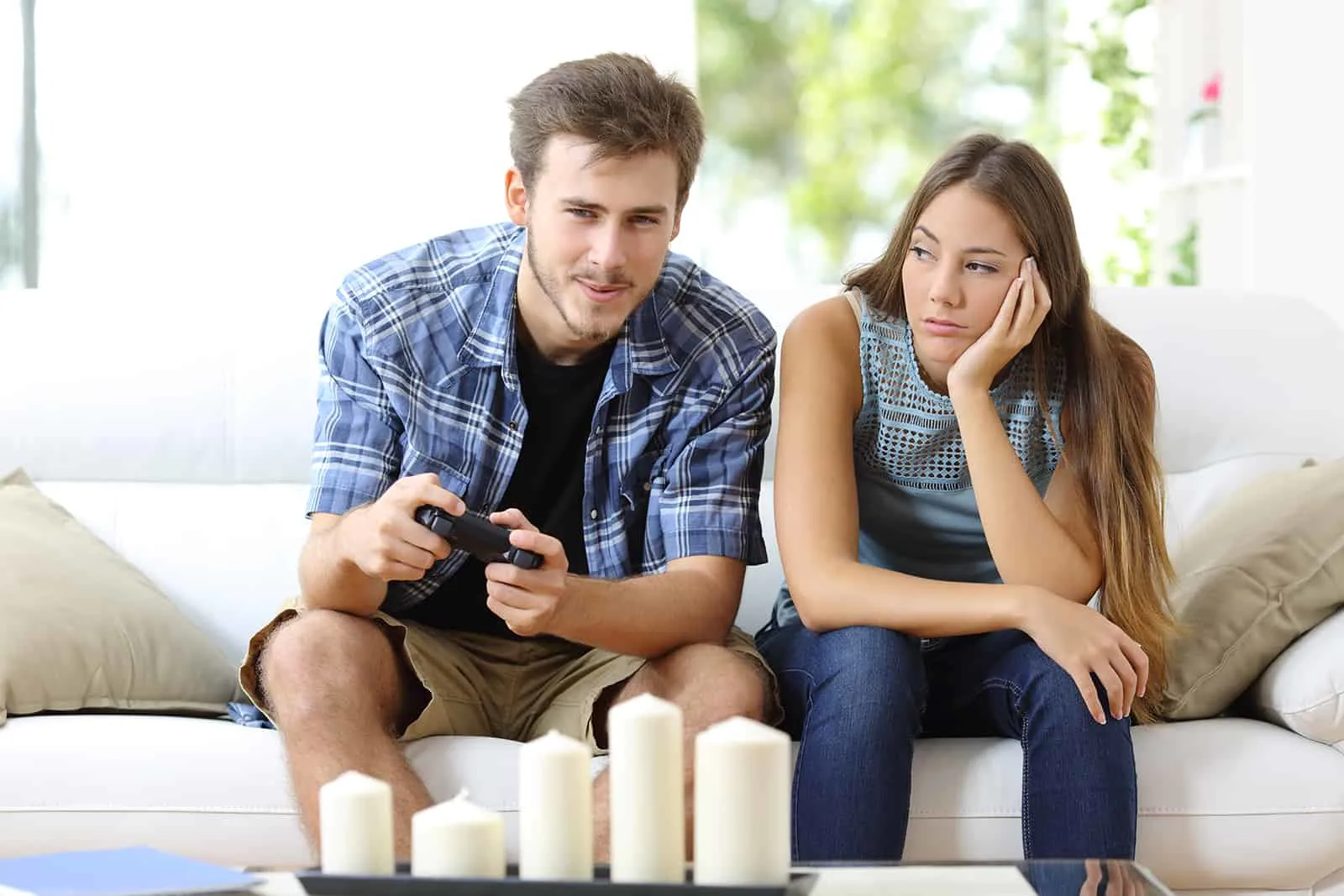 Mann, der Videospiele zu Hause neben ihrer Freundin spielt, gelangweilt neben dem Blick auf ihn