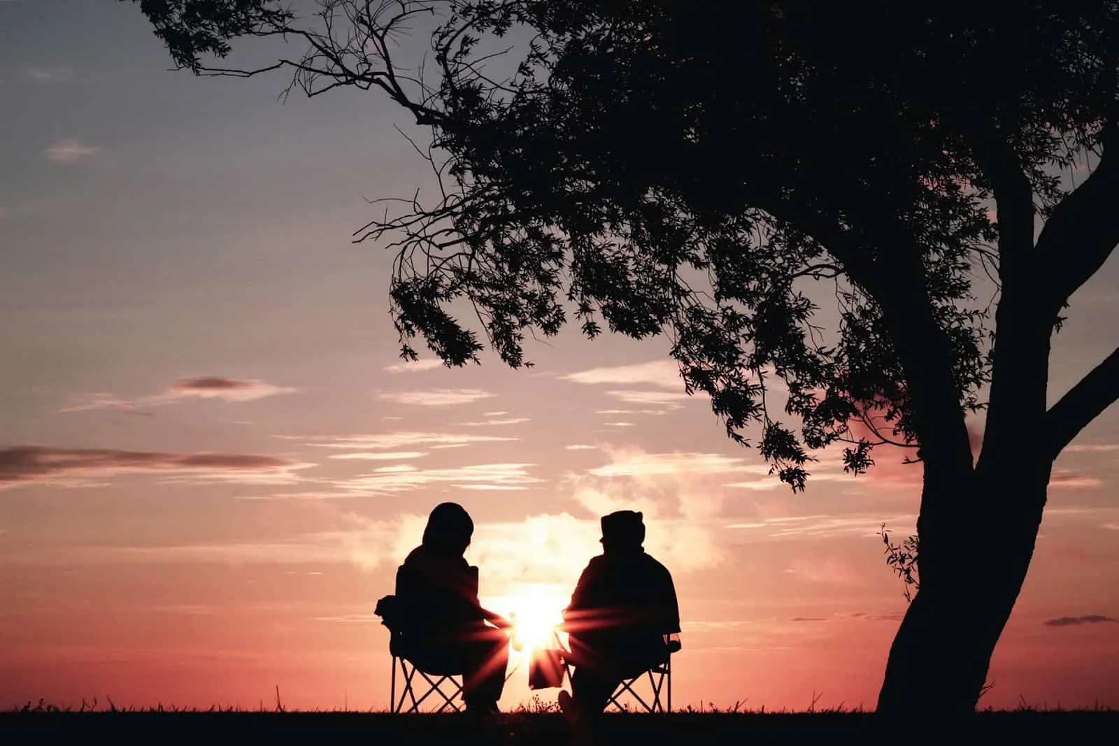 Paar sitzt auf den Stühlen und beobachtet den Sonnenaufgang in der Natur