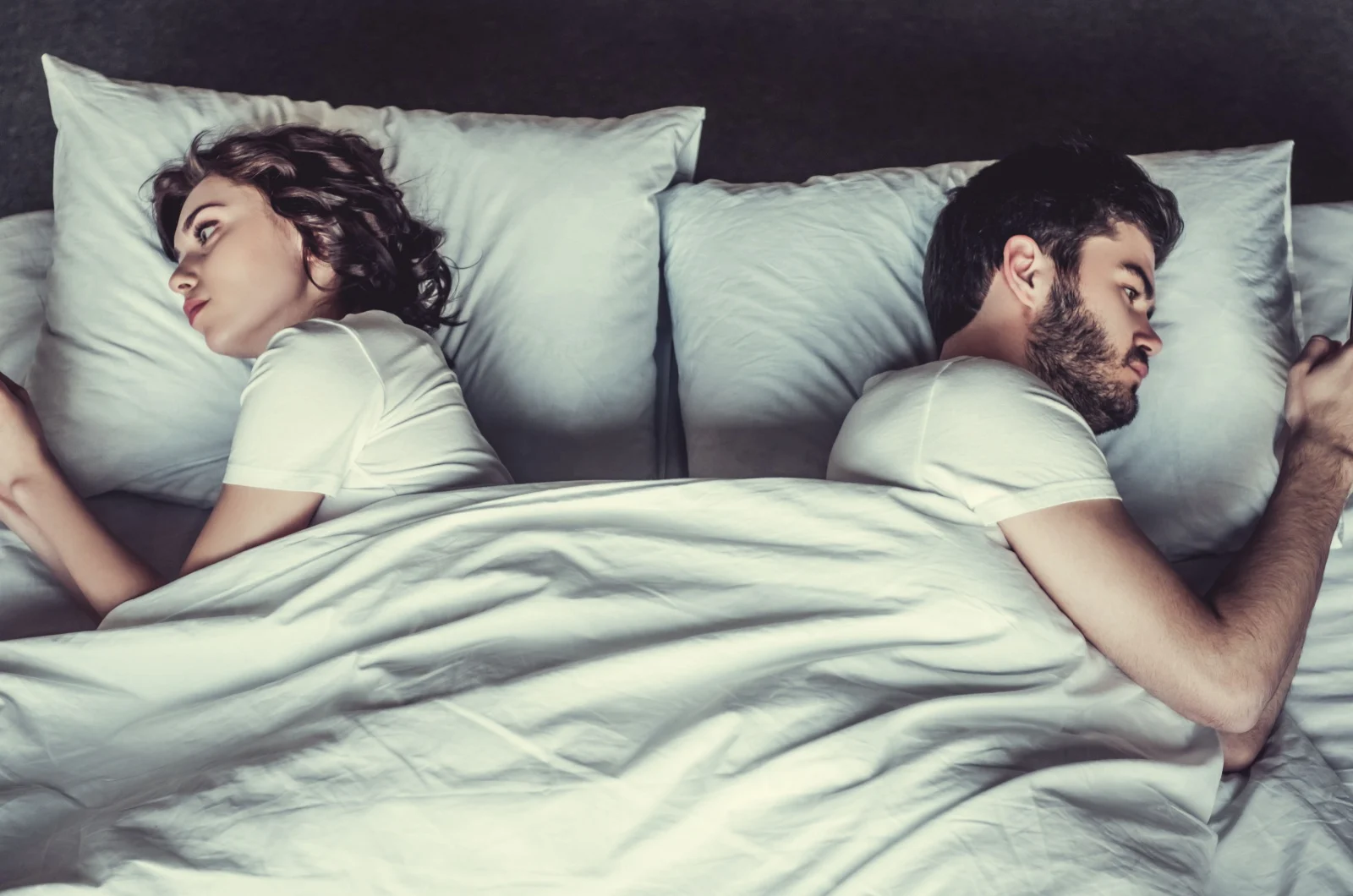 Paar telefoniert im Bett