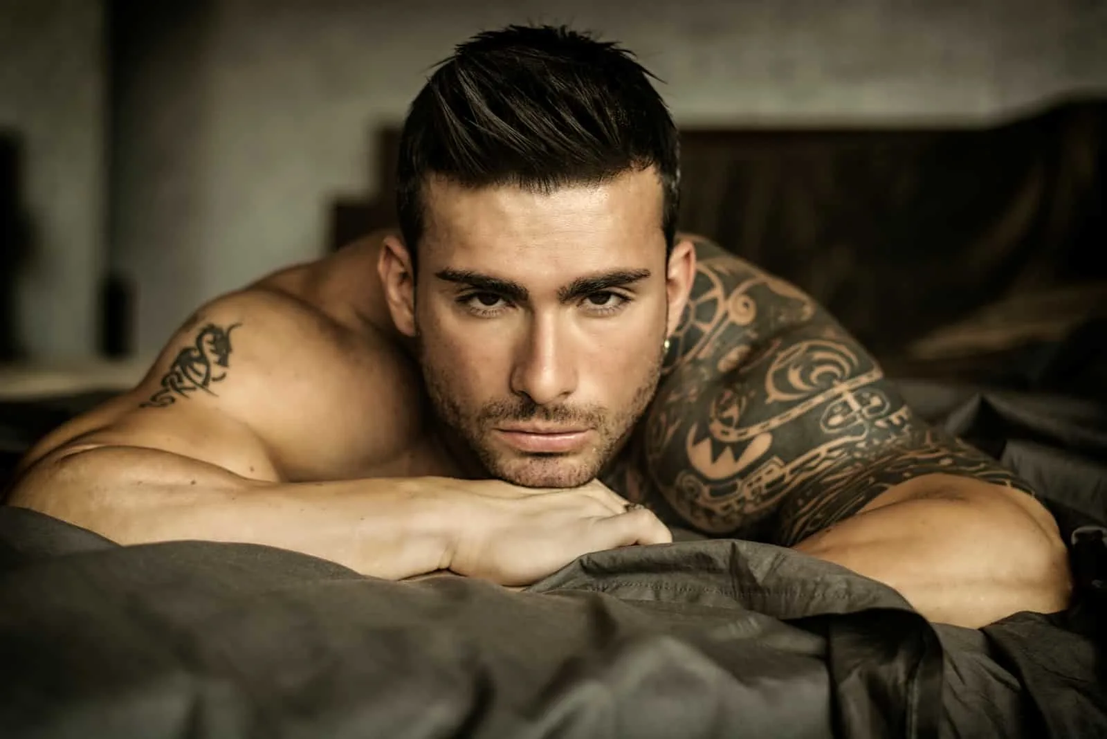 ein gutaussehender Mann ohne Hemd im Bett liegend