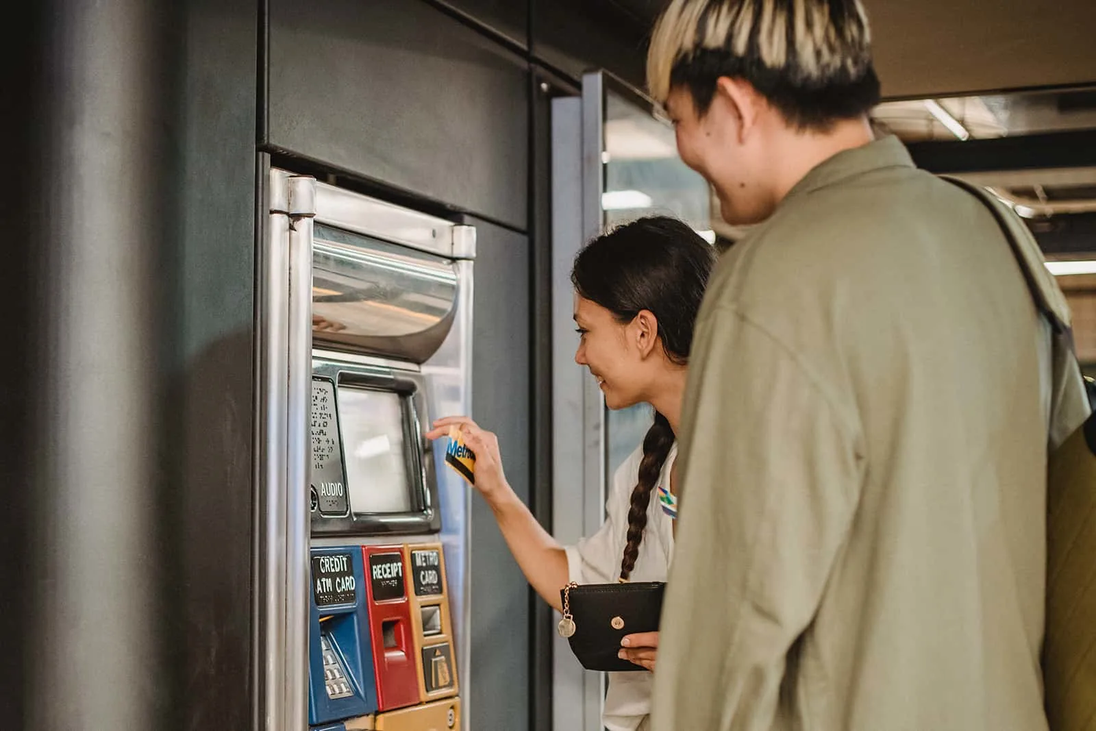 ein Paar, das einen Fahrkartenautomaten in der U-Bahn benutzt
