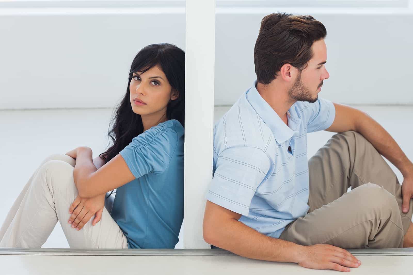 a couple sitting on the floor separated with a wall between them