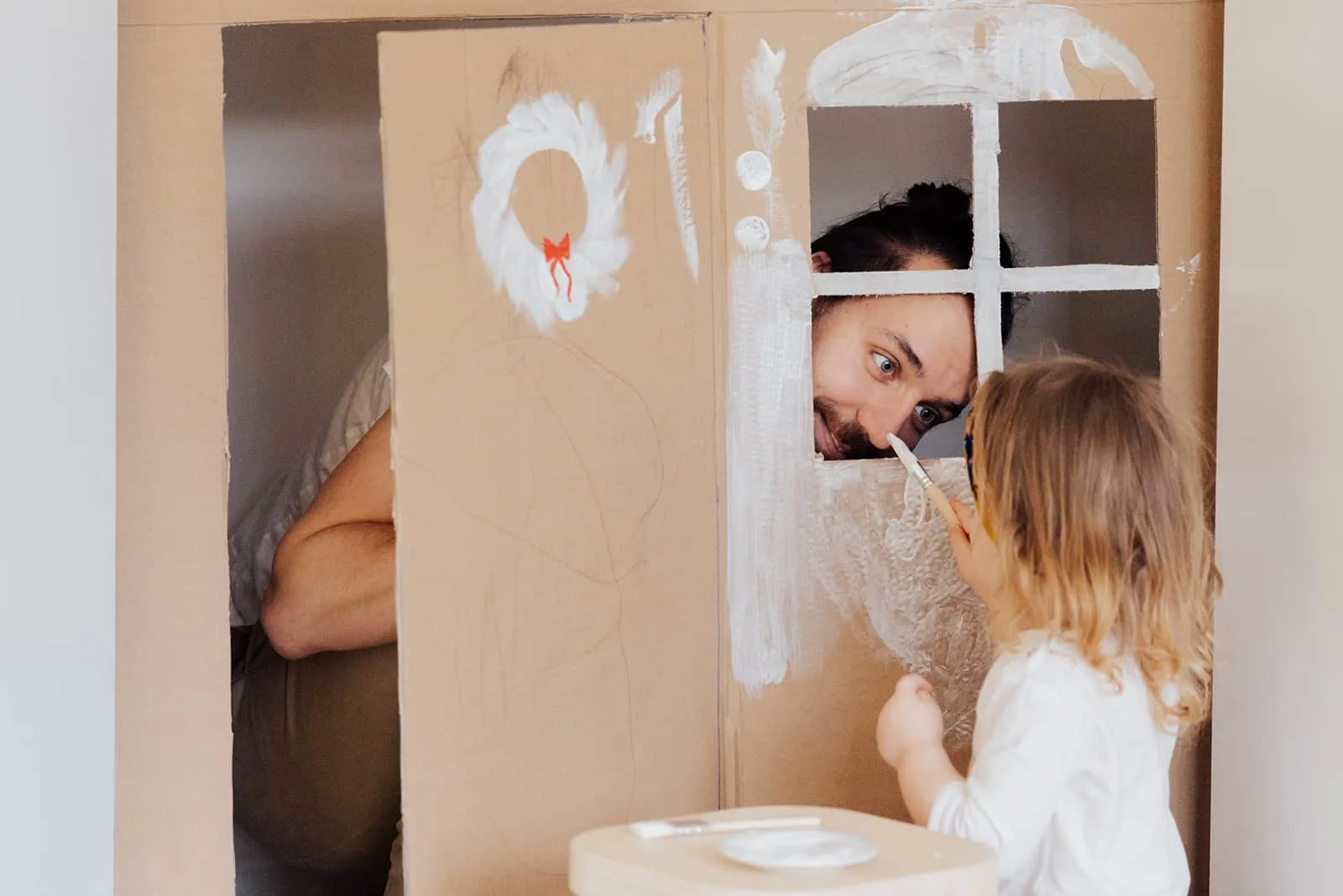 Ein Vater spielt mit einer kleinen Tochter und versteckt sich in einem Karton